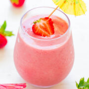 Fresh strawberry smoothie in a glass with a garnish and a cocktail umbrella.
