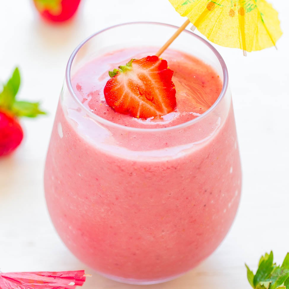 Fresh strawberry smoothie in a glass with a garnish and a cocktail umbrella.