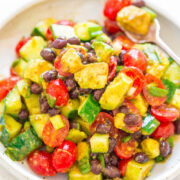 A vibrant salad with avocado, beans, cherry tomatoes, and bell pepper, seasoned with spices.
