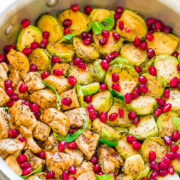 Sautéed chicken and brussels sprouts garnished with pomegranate seeds in a pan.