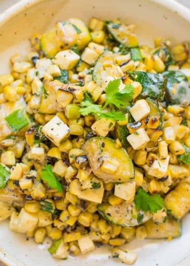 A bowl of grilled corn salad with diced vegetables and herbs.