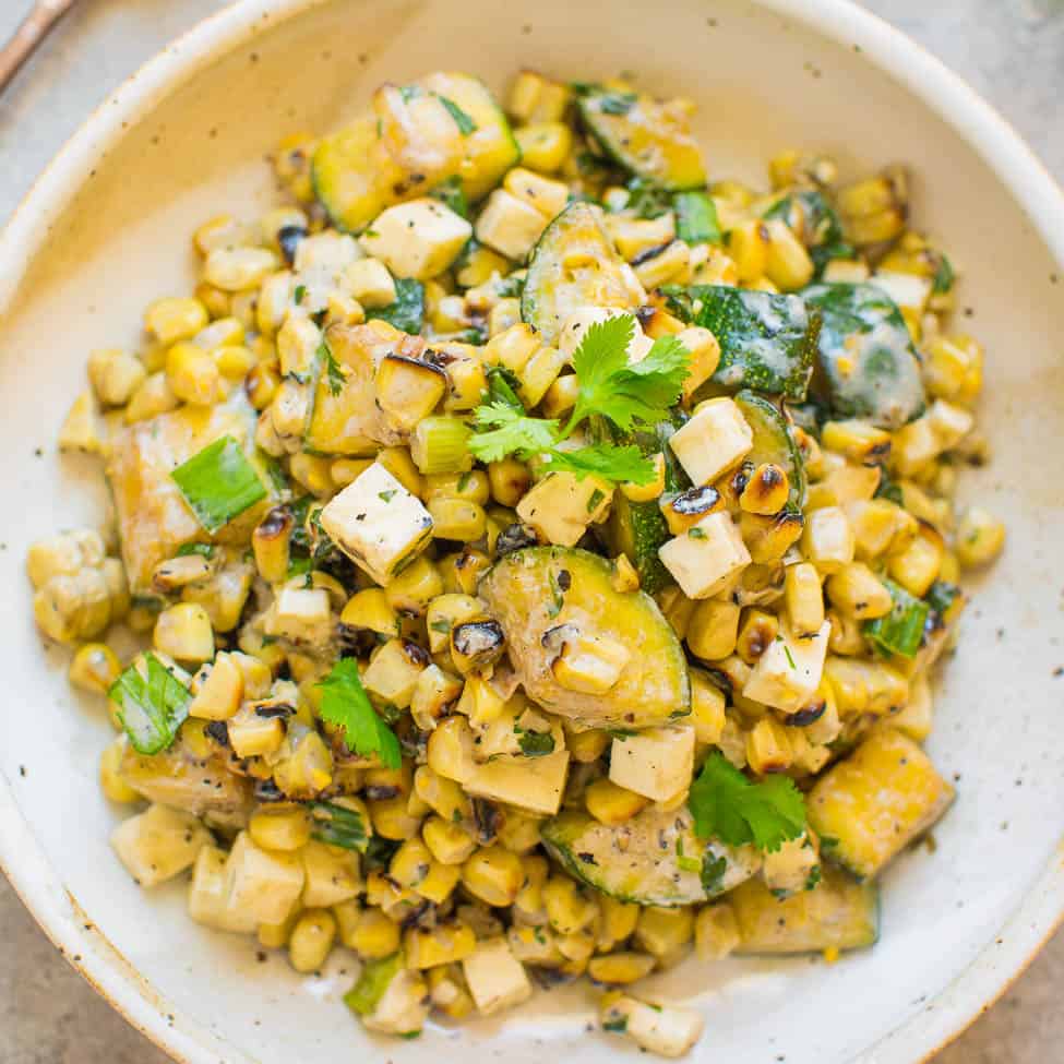 A bowl of grilled corn salad with diced vegetables and herbs.