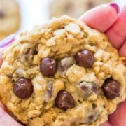 A close-up of a hand holding a chocolate chip oatmeal cookie.