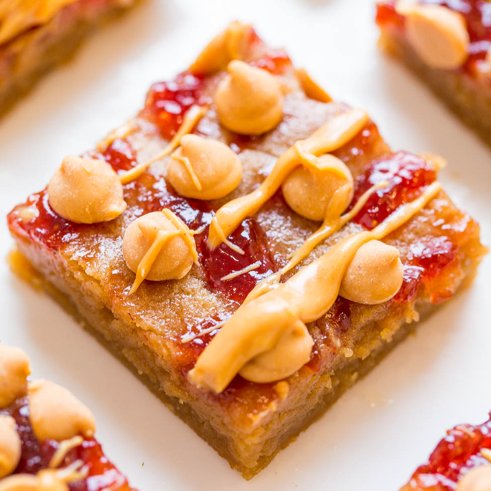 A close-up of a square piece of dessert topped with peanuts and a drizzle of caramel.