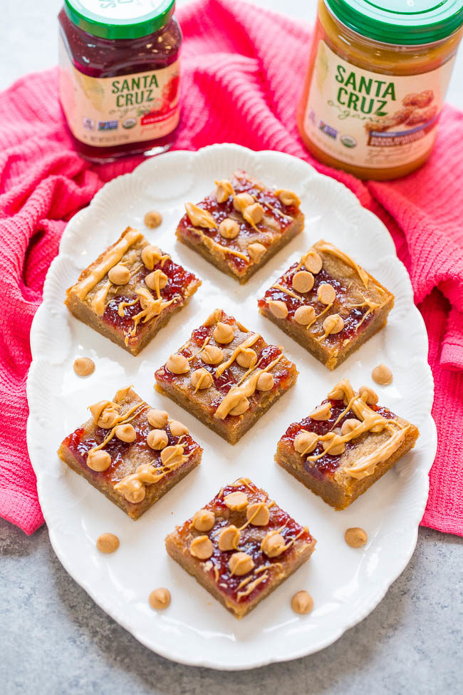 PB & J Bars - Super soft peanut butter bars topped with strawberry jelly, peanut butter chips, and a peanut butter drizzle!! Fast, EASY, and they'll be your new FAVORITE way to eat PB & J!!
