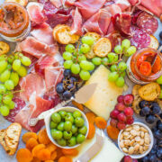 Assorted charcuterie and cheese platter with grapes, nuts, and dried fruits.