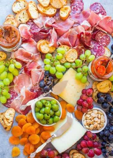 Assorted charcuterie and cheese platter with grapes, nuts, and dried fruits.