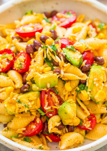 A bowl of pasta salad with avocado, tomatoes, corn, and black beans.