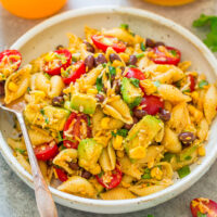A bowl of pasta salad with beans, corn, avocado, and cherry tomatoes.