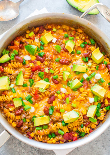 One-pot mexican-inspired pasta dish with beans, cheese, and avocado garnish.