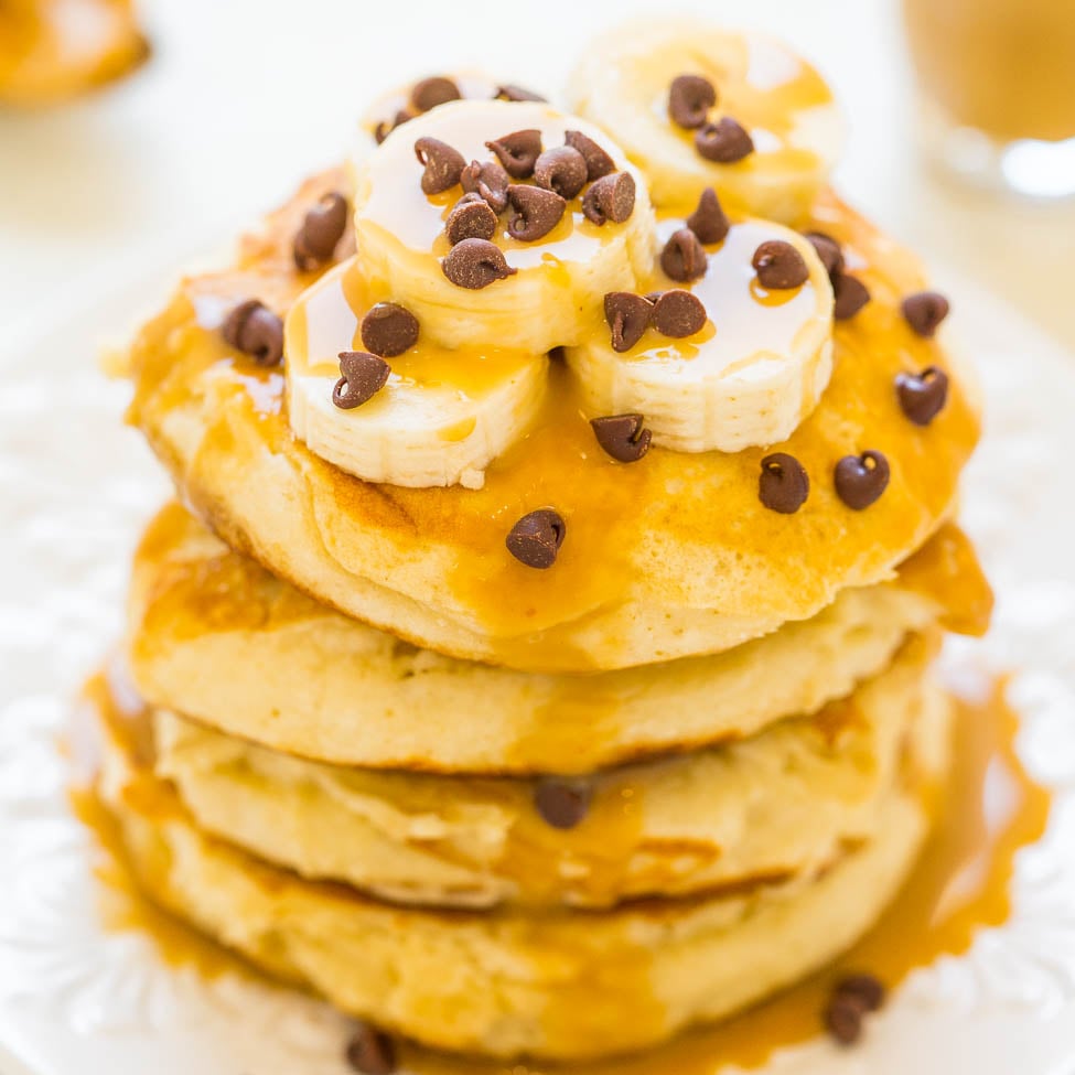 A stack of pancakes topped with banana slices, caramel sauce, and chocolate chips.