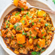 A bowl of vegetable chickpea stew garnished with fresh herbs.