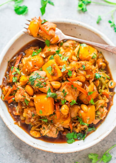 A bowl of vegetable chickpea stew garnished with fresh herbs.