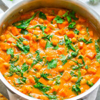 A pot of chickpea and spinach curry served with flatbread.