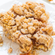 A slice of apple crumble pie on a white plate.