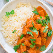 A bowl of chicken tikka masala served with white rice and garnished with fresh cilantro.