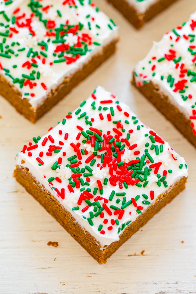 three gingerbread bars topped with cream cheese frosting and holiday sprinkles