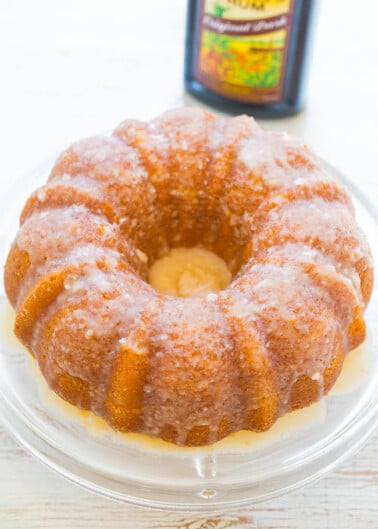 Glazed lemon bundt cake on a plate with a lemon extract bottle in the background.