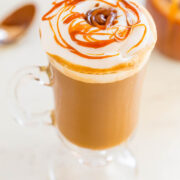 A caramel drizzled latte in a clear mug.