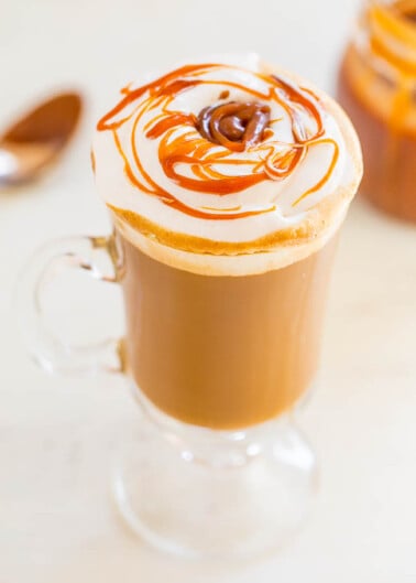 A caramel drizzled latte in a clear mug.