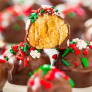 Chocolate-covered treats with holiday sprinkles, one broken open to show a crunchy, crumbly interior.