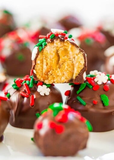Chocolate-covered treats with holiday sprinkles, one broken open to show a crunchy, crumbly interior.