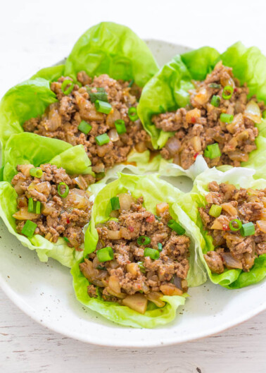 Asian-style ground meat served in lettuce cups on a white plate.