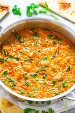 A skillet with creamy tomato spinach pasta sauce, garnished with fresh herbs.