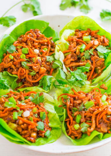 Asian-style lettuce wraps filled with savory minced meat and shredded carrots, garnished with green onions and cilantro.