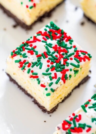 A festive cheesecake bar with sprinkles on top, displayed on a white surface.