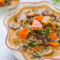 A bowl of wild rice and mushroom soup garnished with fresh herbs.