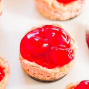 Mini cherry cheesecakes on a white surface.