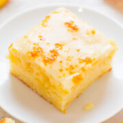 A slice of citrus-glazed cake on a white plate, with orange slices in the background.