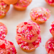 A stack of pink cupcakes adorned with red and pink sprinkles and heart-shaped toppings.
