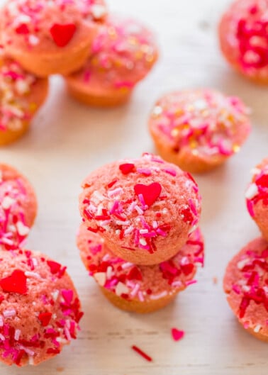 A stack of pink cupcakes adorned with red and pink sprinkles and heart-shaped toppings.