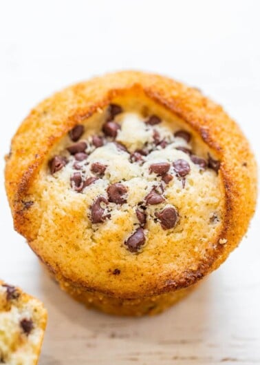 Close-up of a freshly baked chocolate chip muffin on a wooden surface.