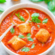 Bowl of tomato basil soup with croutons on top.