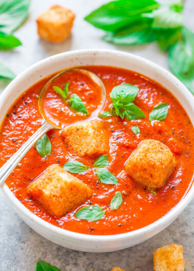 Bowl of tomato basil soup with croutons on top.