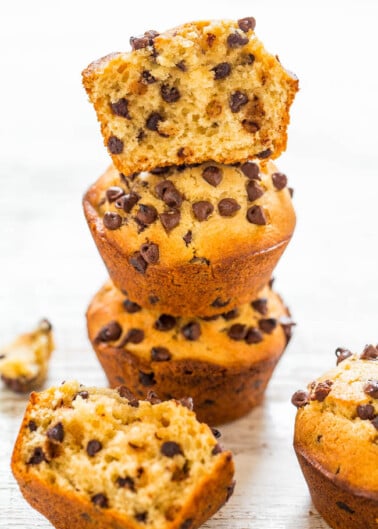 A stack of chocolate chip muffins on a wooden surface.