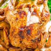 Roasted chicken with golden-brown skin served with herbs and roasted fingerling potatoes.