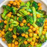 A bowl full of roasted broccoli and chickpeas garnished with herbs.