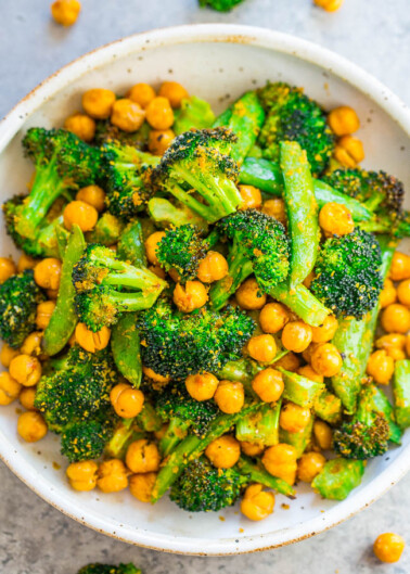 A bowl full of roasted broccoli and chickpeas garnished with herbs.