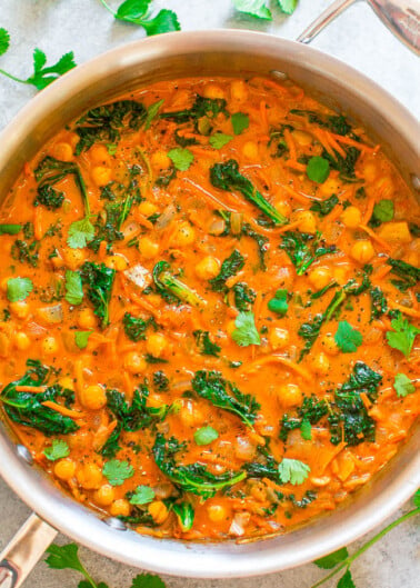 A pot of chickpea and spinach curry garnished with cilantro.