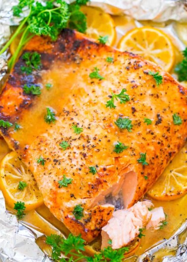 Oven-baked salmon fillet seasoned with spices, garnished with parsley and lemon slices.