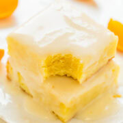 A slice of creamy layered dessert with an orange-flavored filling on a white plate, garnished with orange segments.
