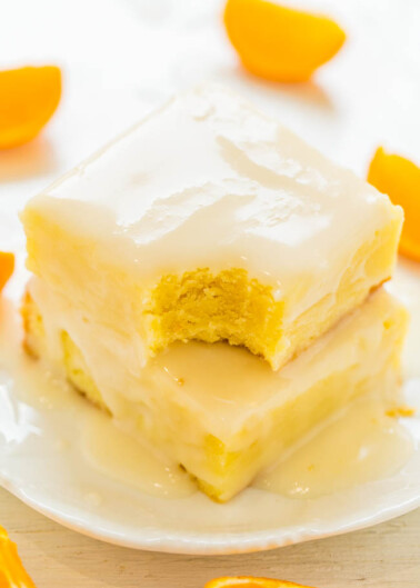 A slice of creamy layered dessert with an orange-flavored filling on a white plate, garnished with orange segments.