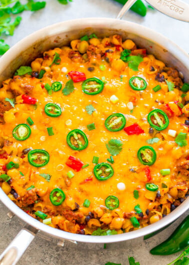 A skillet of cheesy ground beef and macaroni topped with sliced jalapeños and fresh cilantro.