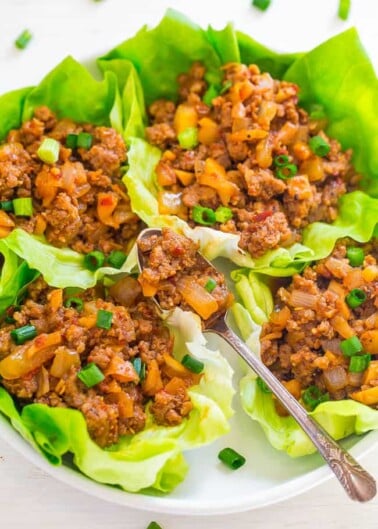 Stuffed lettuce cups with savory ground meat and diced vegetables, garnished with chopped green onions.