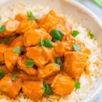 A dish of chicken tikka masala served over white rice, garnished with fresh cilantro.