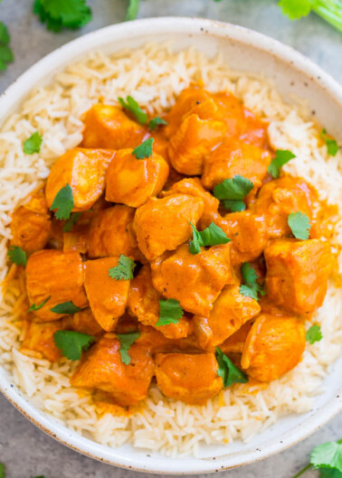 A bowl of chicken tikka masala served over white rice, garnished with cilantro.